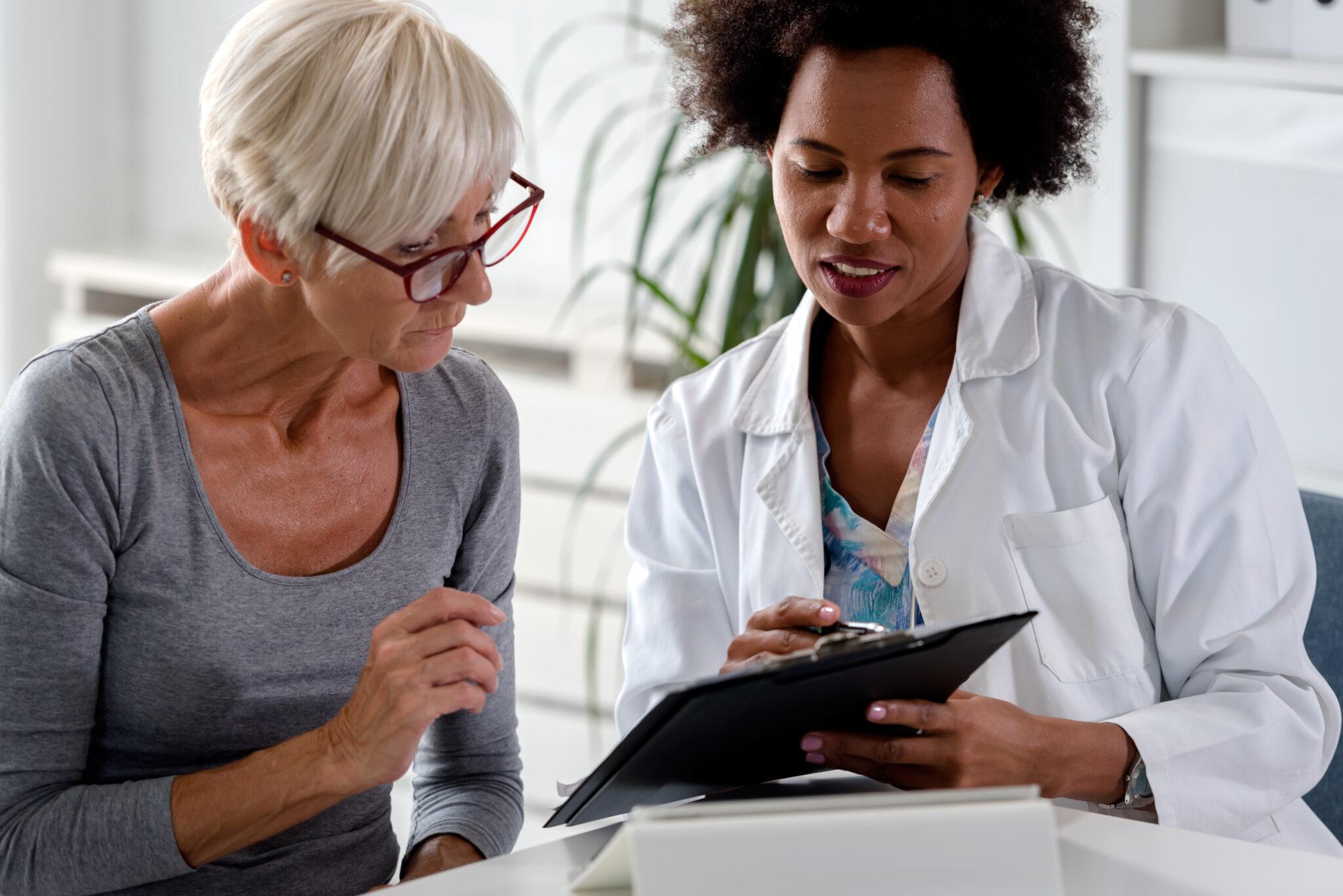 Dietitians speaks to a patient while reviewing notes on a clipboard