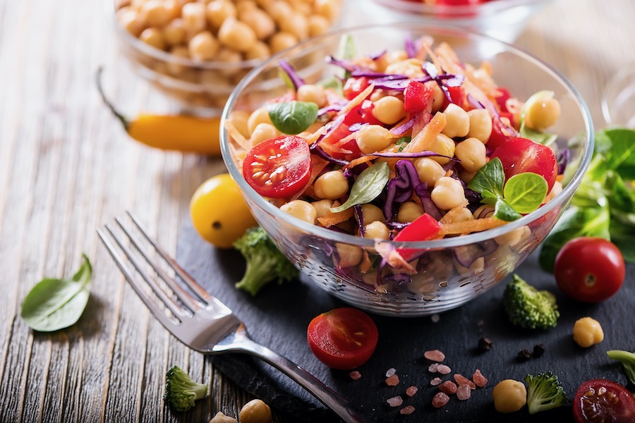 bowl full of chick peas, herbs, slaw, tomatoes next to fork
