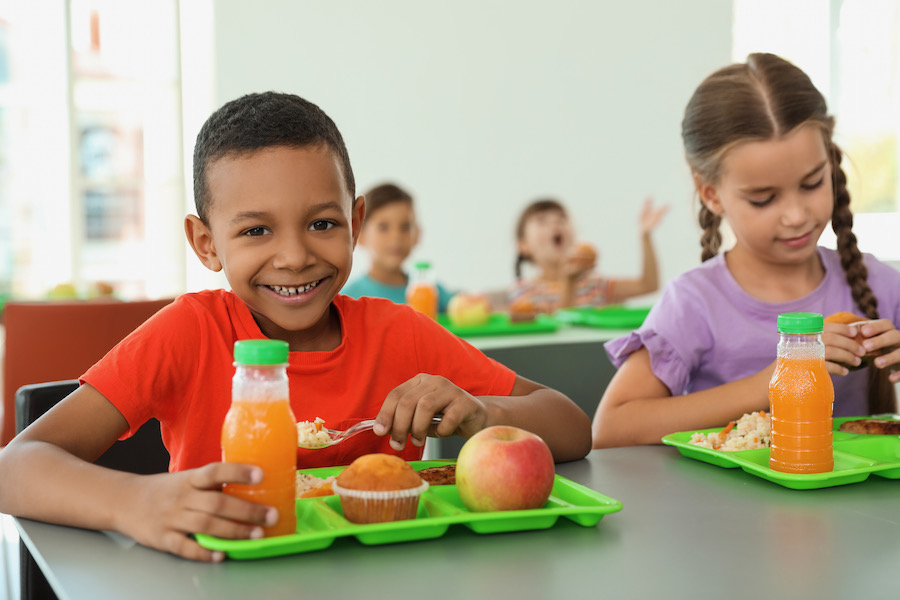Children sitting at table and eating healthy food during break at school