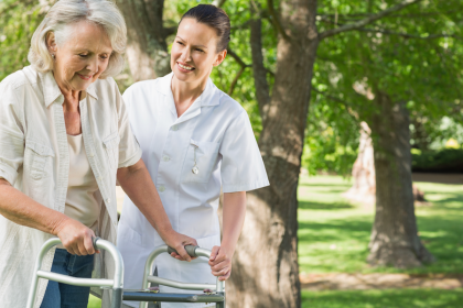 Nurse helping elderly woman walk with a walker