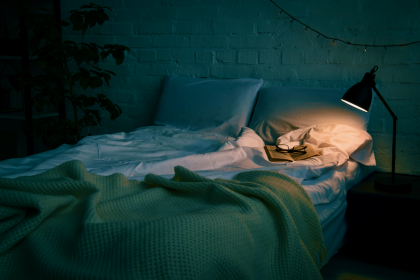 Empty bed during the night with bedside lamp on