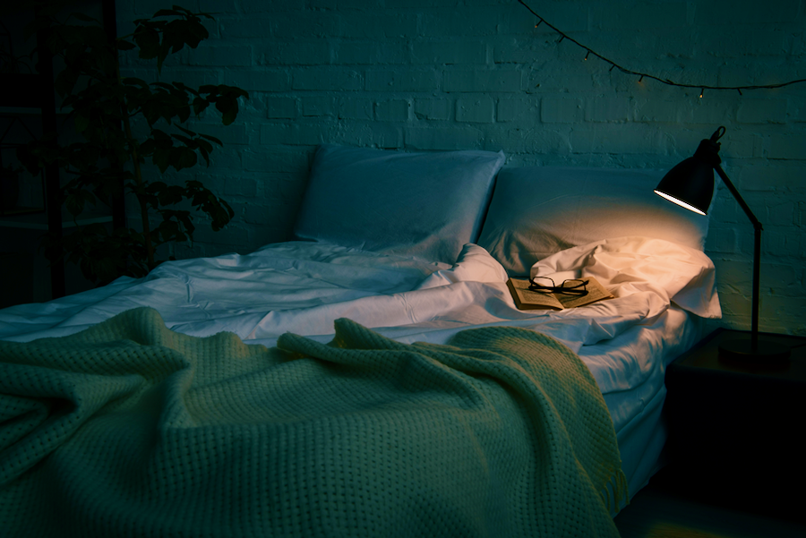 Empty bed during the night with bedside lamp on