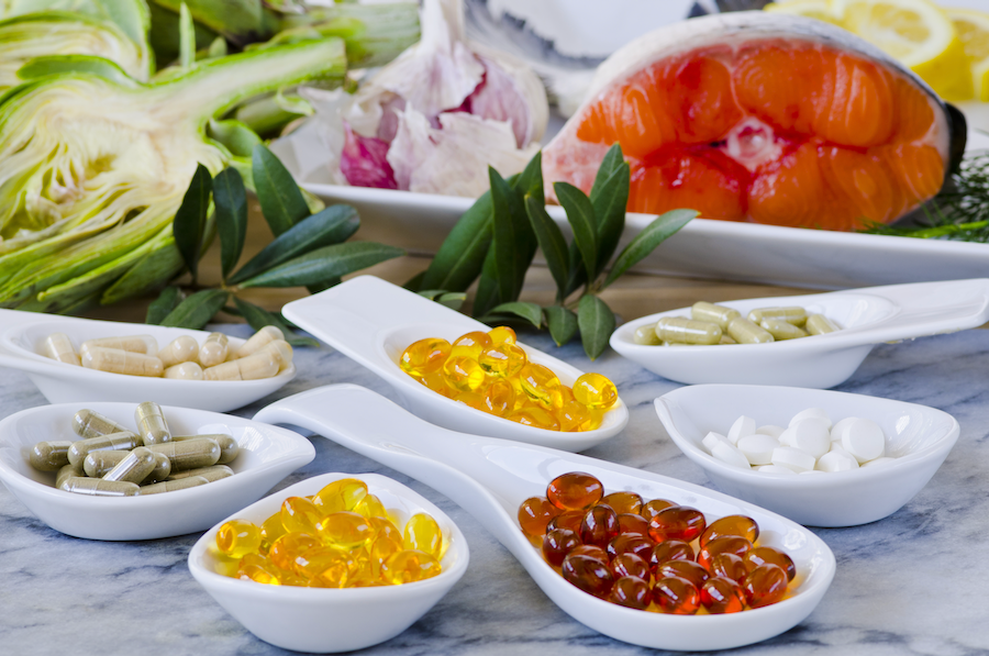 Vitamin and mineral supplements with healthy foods in the background