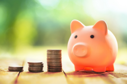 Cute piggy bank next to stacks of coins