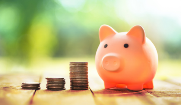 Cute piggy bank next to stacks of coins