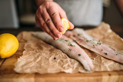 person squeezing lemon onto fish_Dietitians On Demand