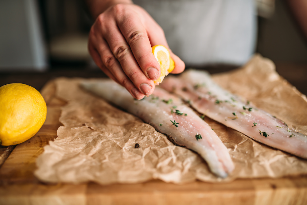 person squeezing lemon onto fish_Dietitians On Demand