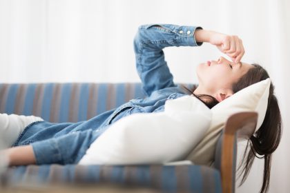 A patient laying back on a couch with a headache